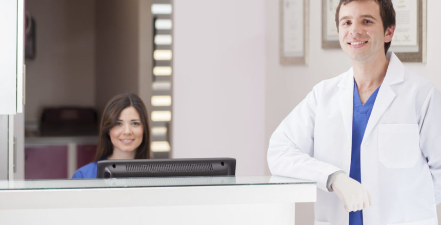 Male dentist and assistant greeting patients at the front desk